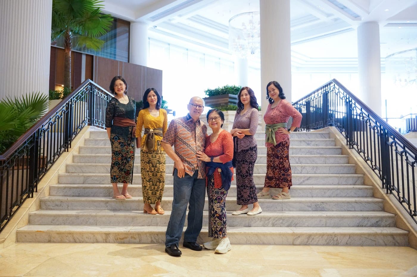 Six family members posing together on indoor stairs