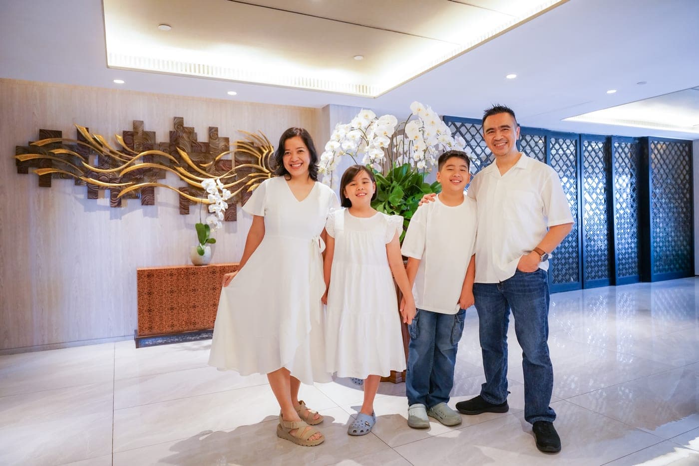 Four family members in white standing together beside orchids