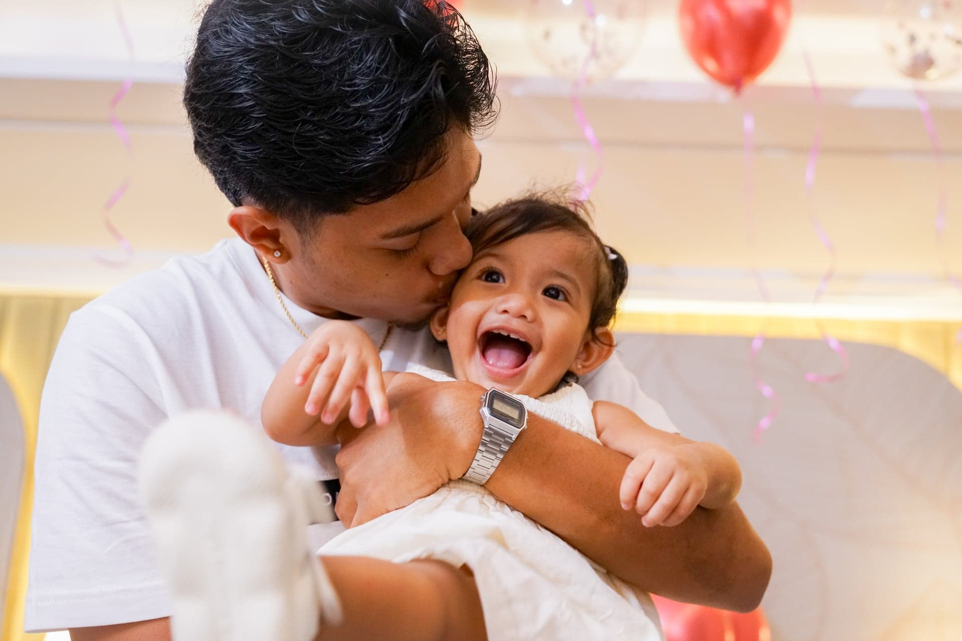 Man kissing the cheek of a laughing child in his arms
